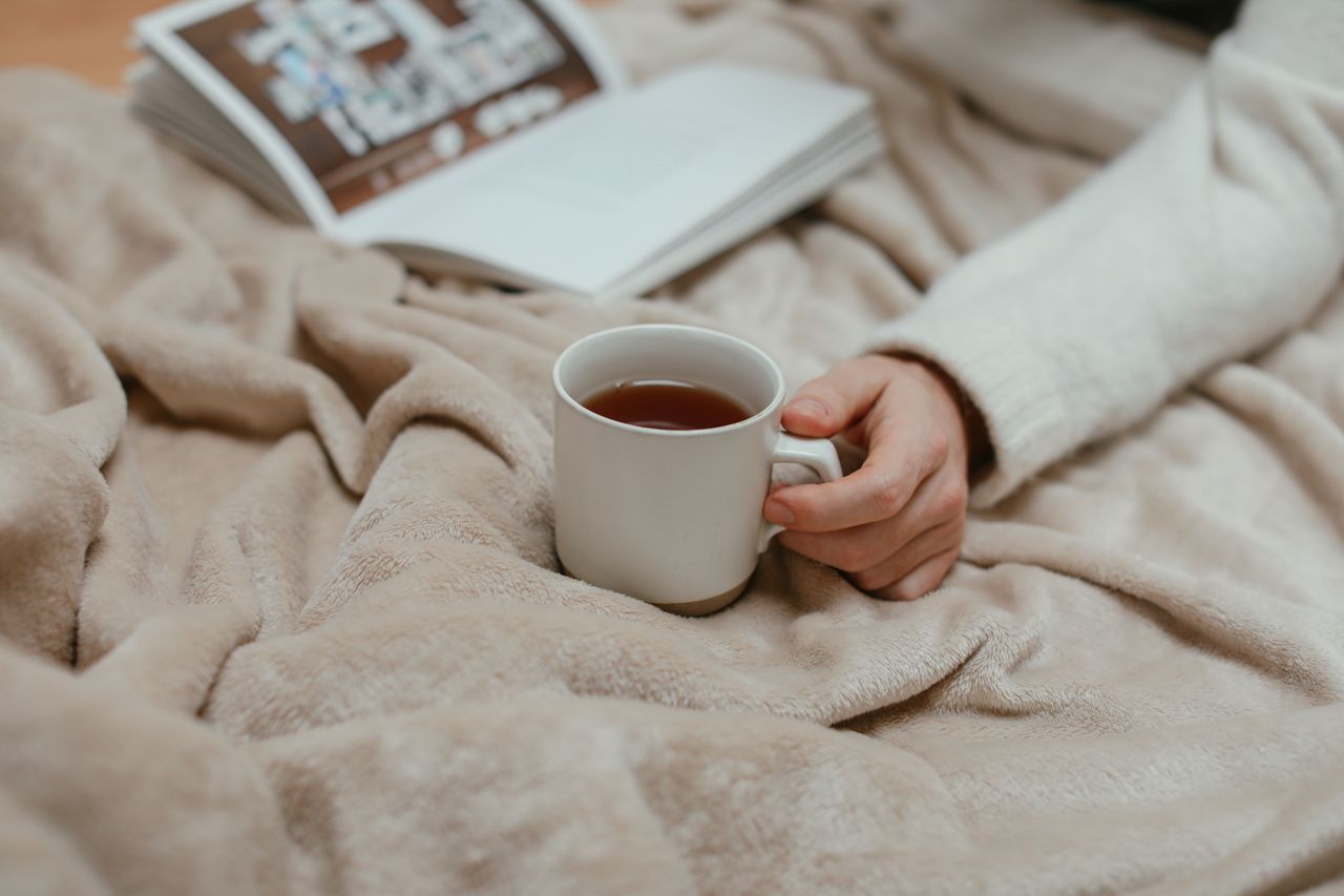 Relax with a warm cup of tea in bed, enjoying a peaceful morning with a book.